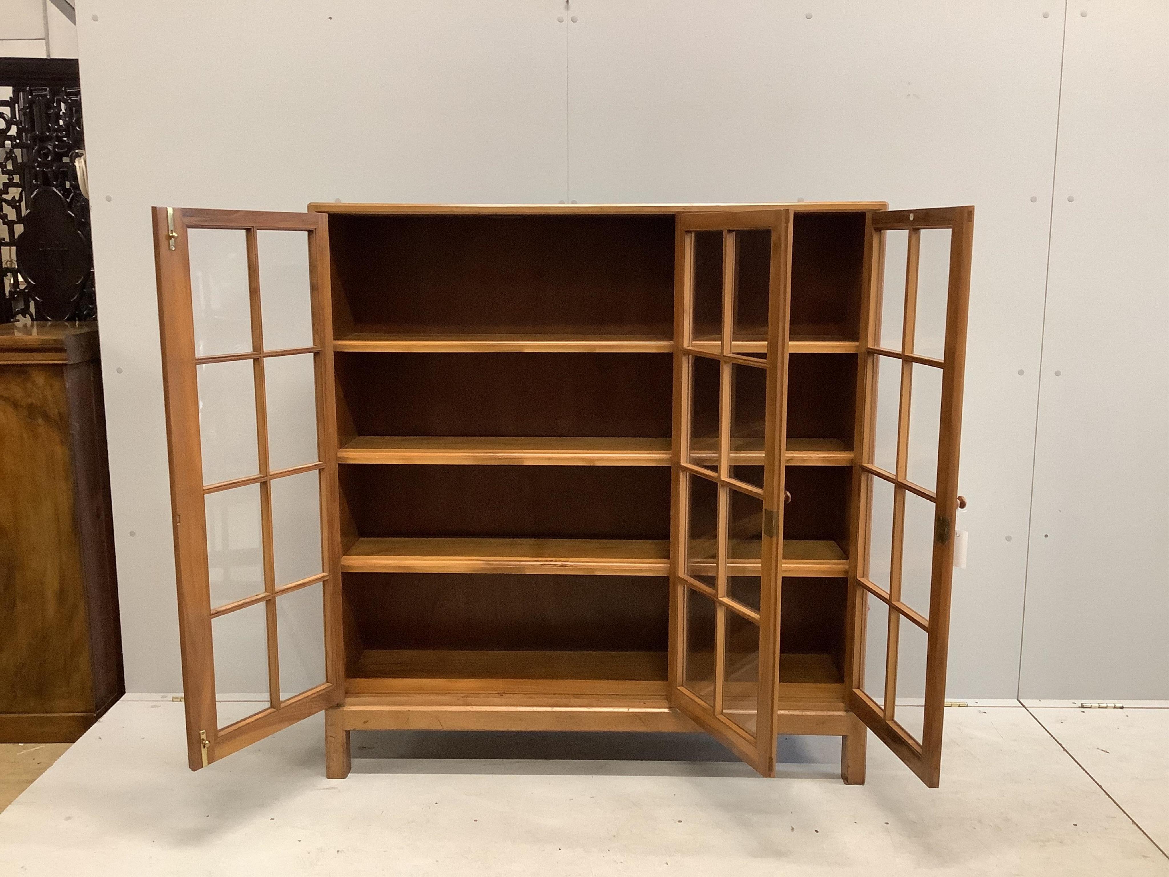 An early 20th century Heal & Son, London glazed walnut three door bookcase, width 122cm, depth 29cm, height 130cm. Condition - fair to good